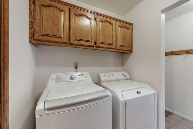 laundry room with cabinets, washer and dryer, and light tile patterned floors