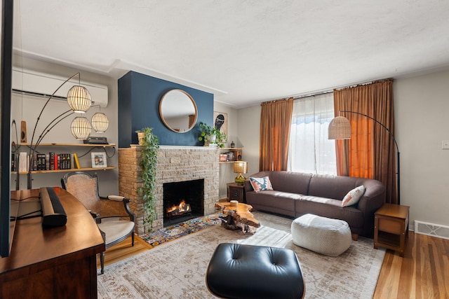 living room with wood-type flooring, a brick fireplace, and a textured ceiling