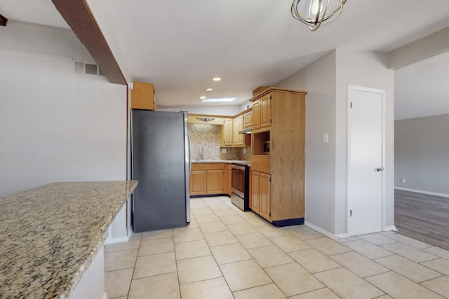 kitchen featuring sink, tasteful backsplash, light tile patterned floors, stainless steel appliances, and light stone countertops