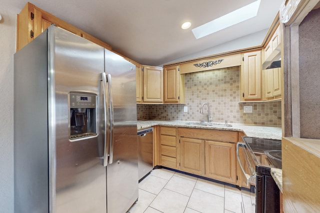 kitchen featuring sink, light tile patterned floors, backsplash, stainless steel appliances, and vaulted ceiling with skylight