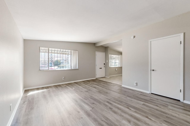 empty room with lofted ceiling and light wood-type flooring