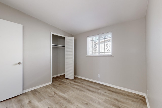 unfurnished bedroom with lofted ceiling, light hardwood / wood-style floors, and a closet