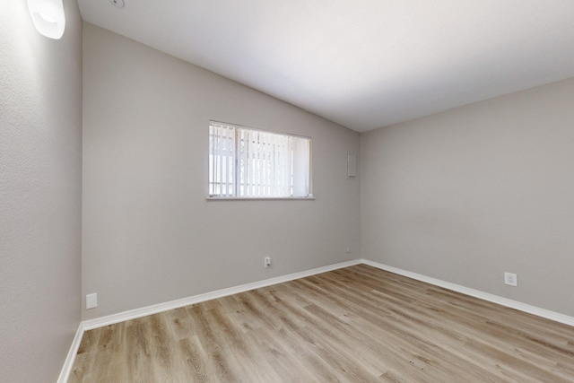 unfurnished room with vaulted ceiling and light hardwood / wood-style flooring