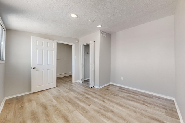 unfurnished bedroom with light hardwood / wood-style floors, a closet, and a textured ceiling