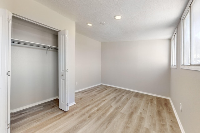 unfurnished bedroom with a closet, a textured ceiling, and light wood-type flooring