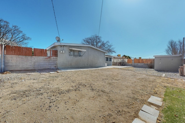 back of house with a storage unit