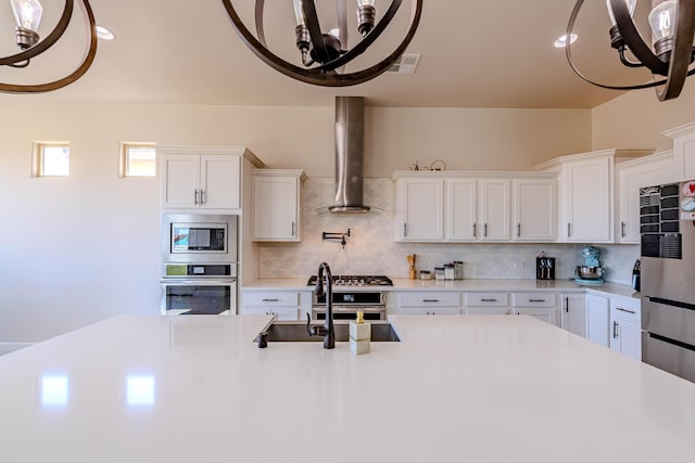 kitchen with stainless steel microwave, tasteful backsplash, sink, white cabinets, and wall chimney exhaust hood