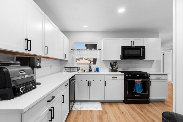 kitchen featuring sink, white cabinetry, tasteful backsplash, light hardwood / wood-style floors, and black appliances