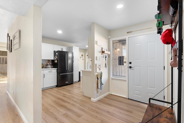 foyer entrance with recessed lighting, light wood-style flooring, and baseboards