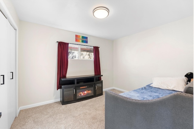 bedroom featuring a glass covered fireplace, a closet, carpet flooring, and baseboards