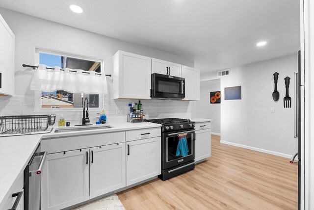 kitchen with sink, tasteful backsplash, black appliances, light hardwood / wood-style flooring, and white cabinets