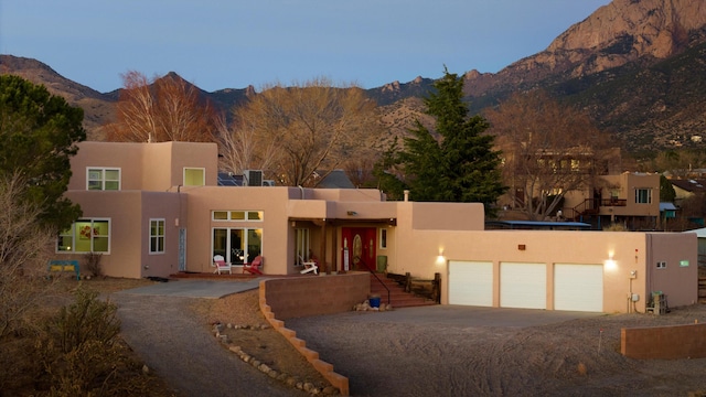 pueblo-style house with a garage and a mountain view