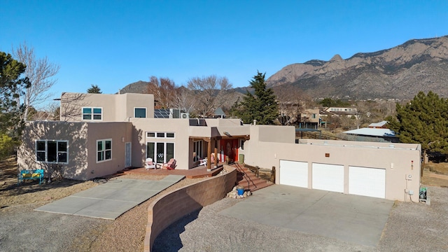 pueblo-style house featuring a garage and a mountain view