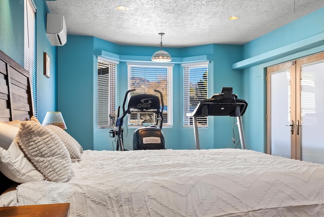 bedroom featuring a wall unit AC, french doors, and a textured ceiling