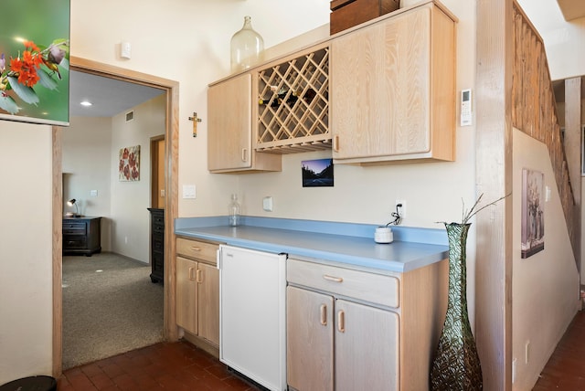 kitchen featuring fridge and light brown cabinetry