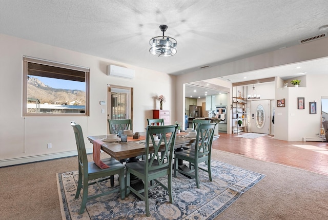 carpeted dining area with a notable chandelier, a mountain view, a wall unit AC, and a textured ceiling