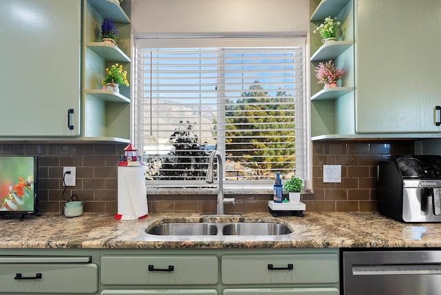 kitchen featuring tasteful backsplash, sink, stainless steel dishwasher, green cabinetry, and light stone countertops