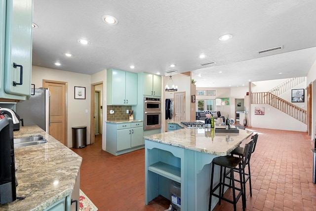 kitchen with a kitchen breakfast bar, stainless steel appliances, a center island, tasteful backsplash, and light stone countertops