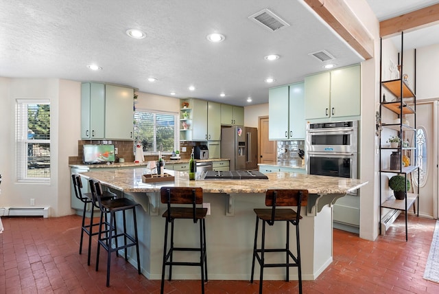 kitchen with a kitchen bar, a center island, appliances with stainless steel finishes, green cabinets, and a healthy amount of sunlight