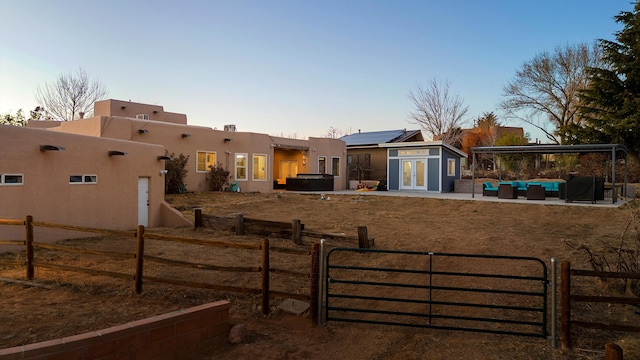 yard at dusk featuring an outdoor living space, a patio, an outdoor structure, and a hot tub