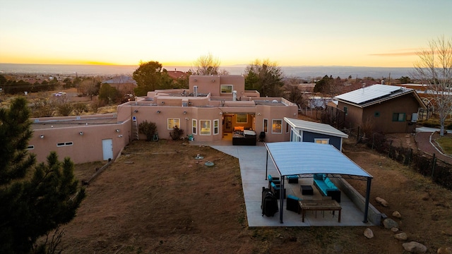 back house at dusk featuring outdoor lounge area and a patio