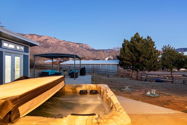 exterior space with a fire pit, a mountain view, a pergola, and french doors