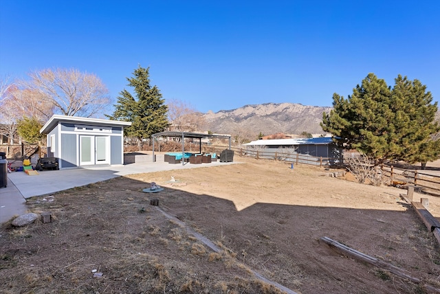 view of yard featuring an outdoor hangout area, an outdoor structure, a mountain view, and a patio