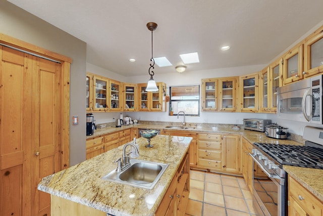 kitchen featuring sink, stainless steel appliances, light stone countertops, and a center island with sink