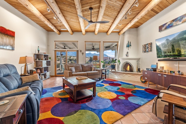 tiled living room featuring ceiling fan, beam ceiling, rail lighting, and wooden ceiling