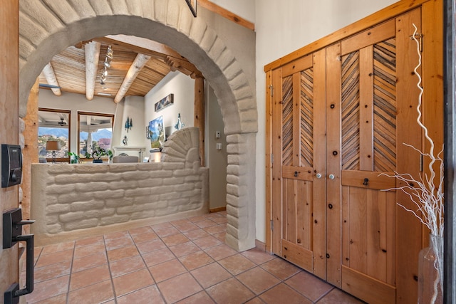 foyer entrance with arched walkways, beamed ceiling, tile patterned floors, and wood ceiling