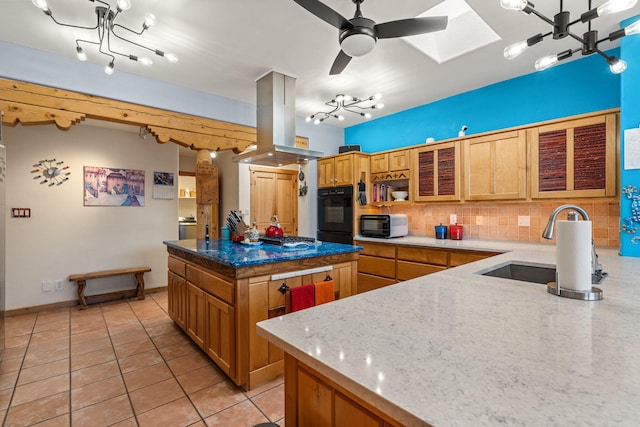 kitchen featuring backsplash, island exhaust hood, black appliances, light stone countertops, and a kitchen island