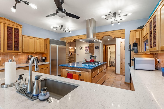 kitchen featuring light tile patterned flooring, island range hood, sink, decorative backsplash, and stainless steel appliances