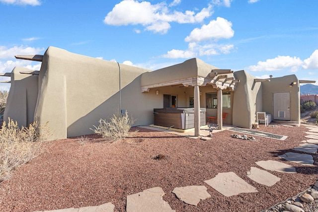 rear view of property with a patio area and a hot tub