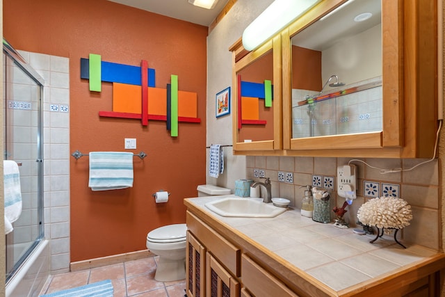 full bathroom featuring toilet, bath / shower combo with glass door, vanity, tile patterned flooring, and decorative backsplash