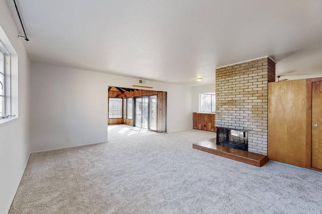 unfurnished living room featuring light colored carpet and a tile fireplace