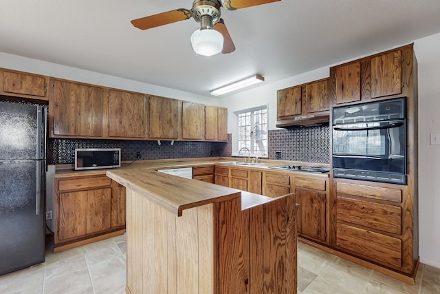 kitchen with sink, ceiling fan, backsplash, a center island, and black appliances