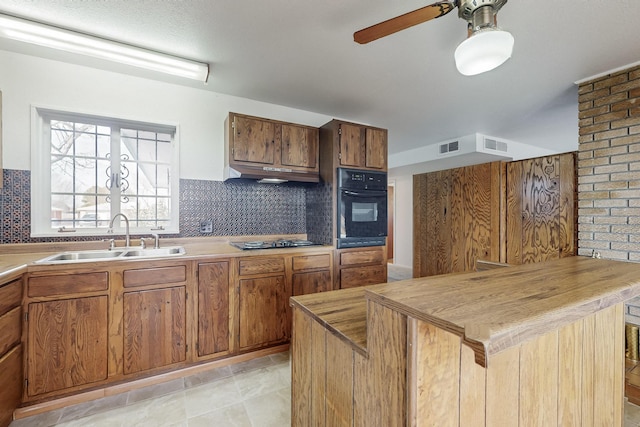 kitchen featuring butcher block countertops, sink, a center island, decorative backsplash, and black appliances