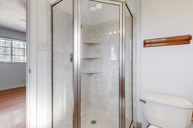 bathroom featuring walk in shower, wood-type flooring, toilet, and a textured ceiling