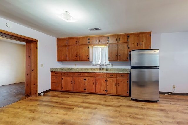 kitchen featuring sink, stainless steel fridge, and light hardwood / wood-style flooring