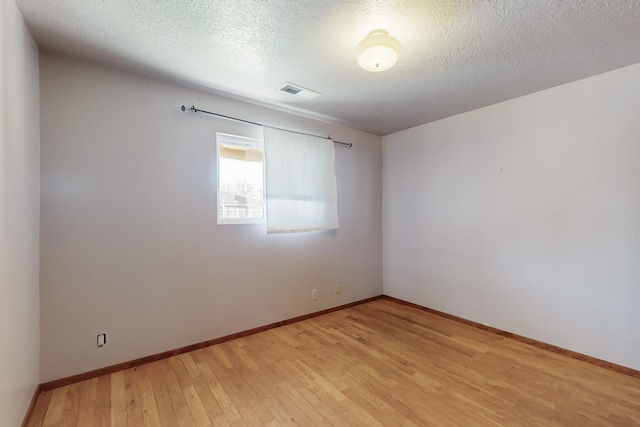 spare room with a textured ceiling and light hardwood / wood-style flooring