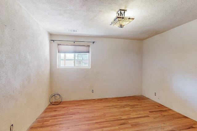 unfurnished room with light hardwood / wood-style floors and a textured ceiling