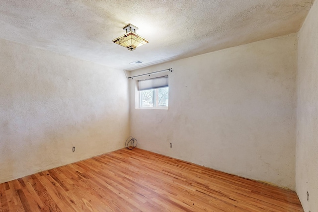 spare room featuring light hardwood / wood-style floors and a textured ceiling