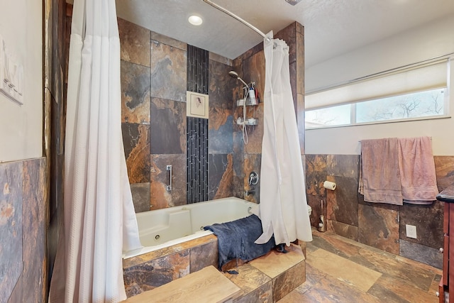 bathroom featuring tile walls and shower / bathtub combination with curtain