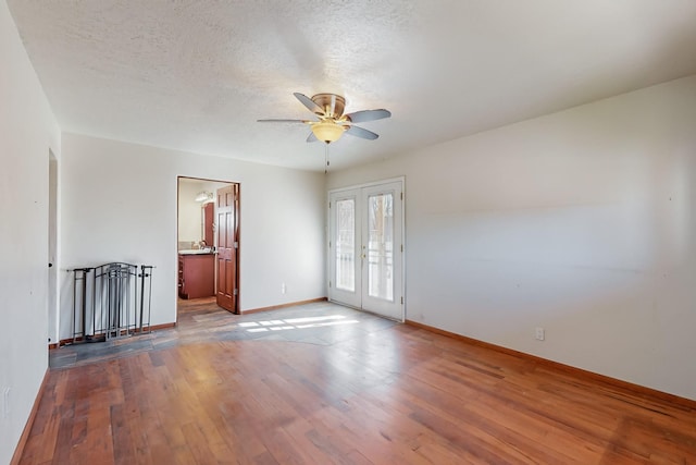 unfurnished room featuring ceiling fan, light hardwood / wood-style flooring, french doors, and a textured ceiling