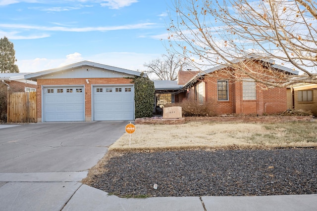 ranch-style home featuring a garage, concrete driveway, brick siding, and fence