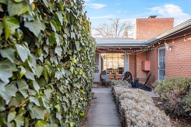 view of home's exterior featuring brick siding, a patio, and a chimney