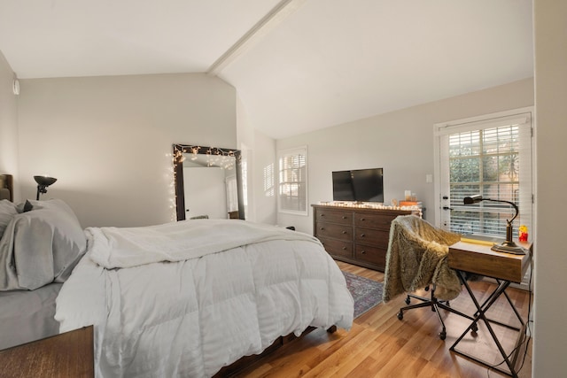 bedroom featuring vaulted ceiling with beams and light wood finished floors