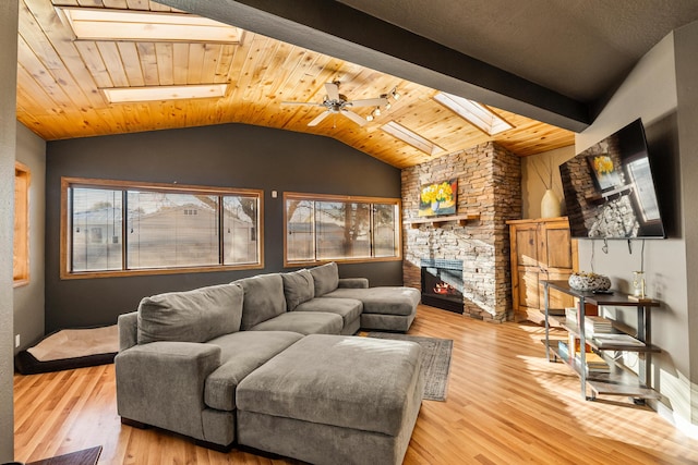 living room with lofted ceiling with skylight, light hardwood / wood-style flooring, wooden ceiling, ceiling fan, and a fireplace