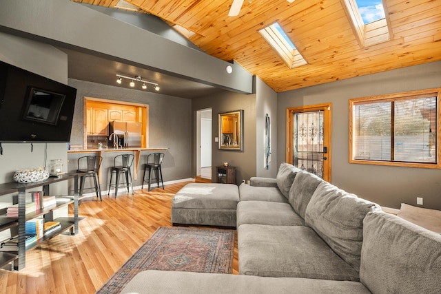 living area with wooden ceiling, light wood finished floors, baseboards, and lofted ceiling with skylight