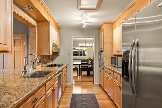 kitchen with tasteful backsplash, sink, stainless steel appliances, light stone countertops, and light hardwood / wood-style flooring